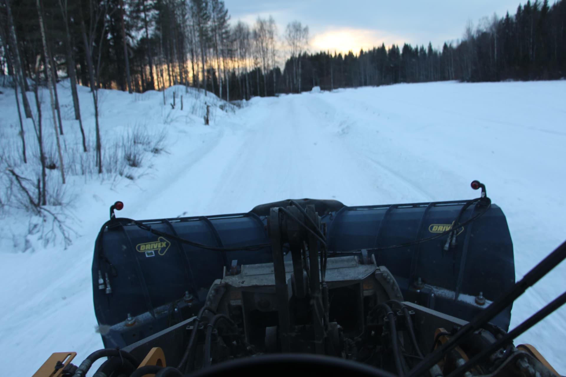 Utsikt från maskinhytt över ett snöblad och en vinterväg
