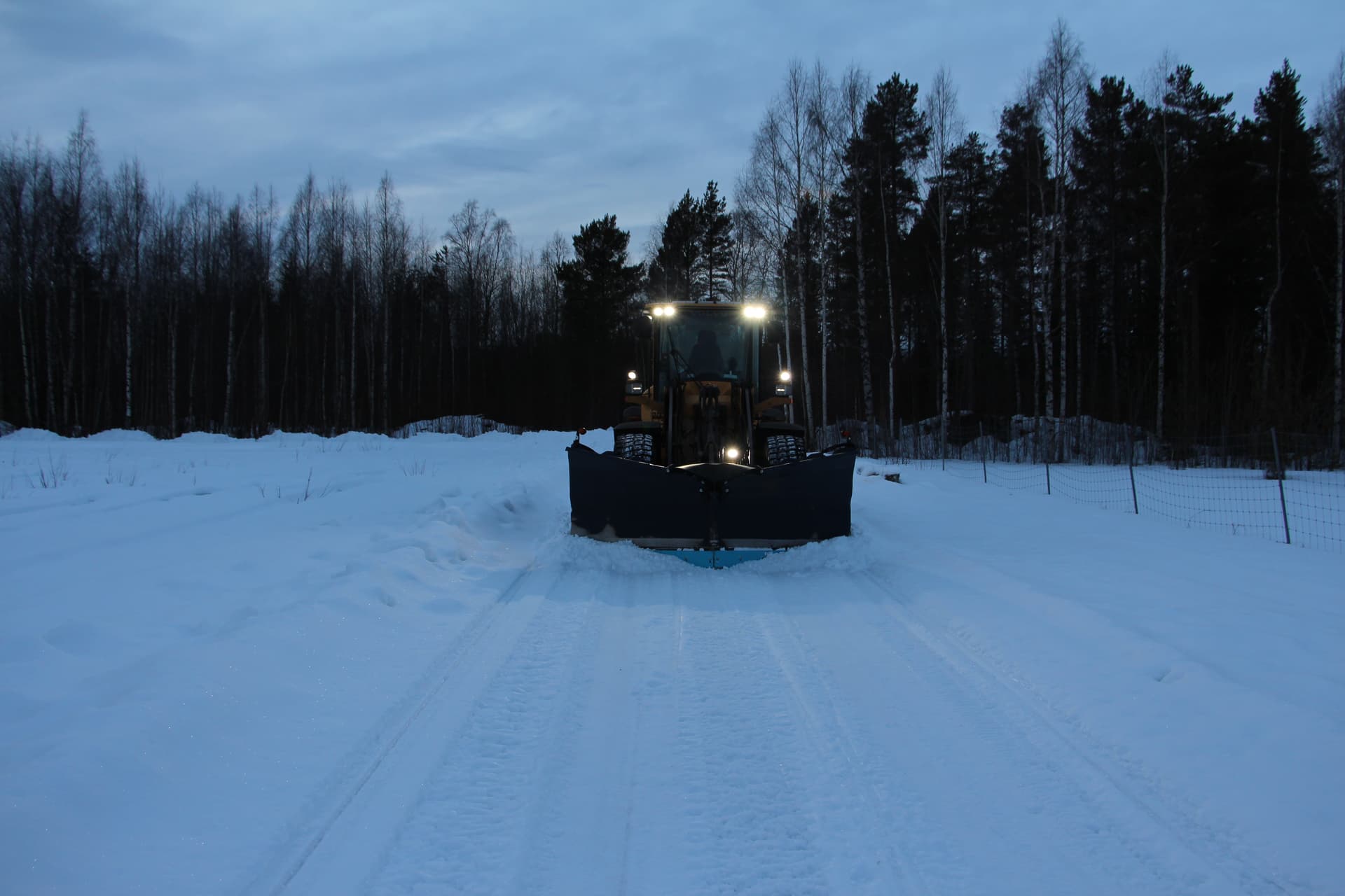 Hjullastare med plog på en snötäckt väg