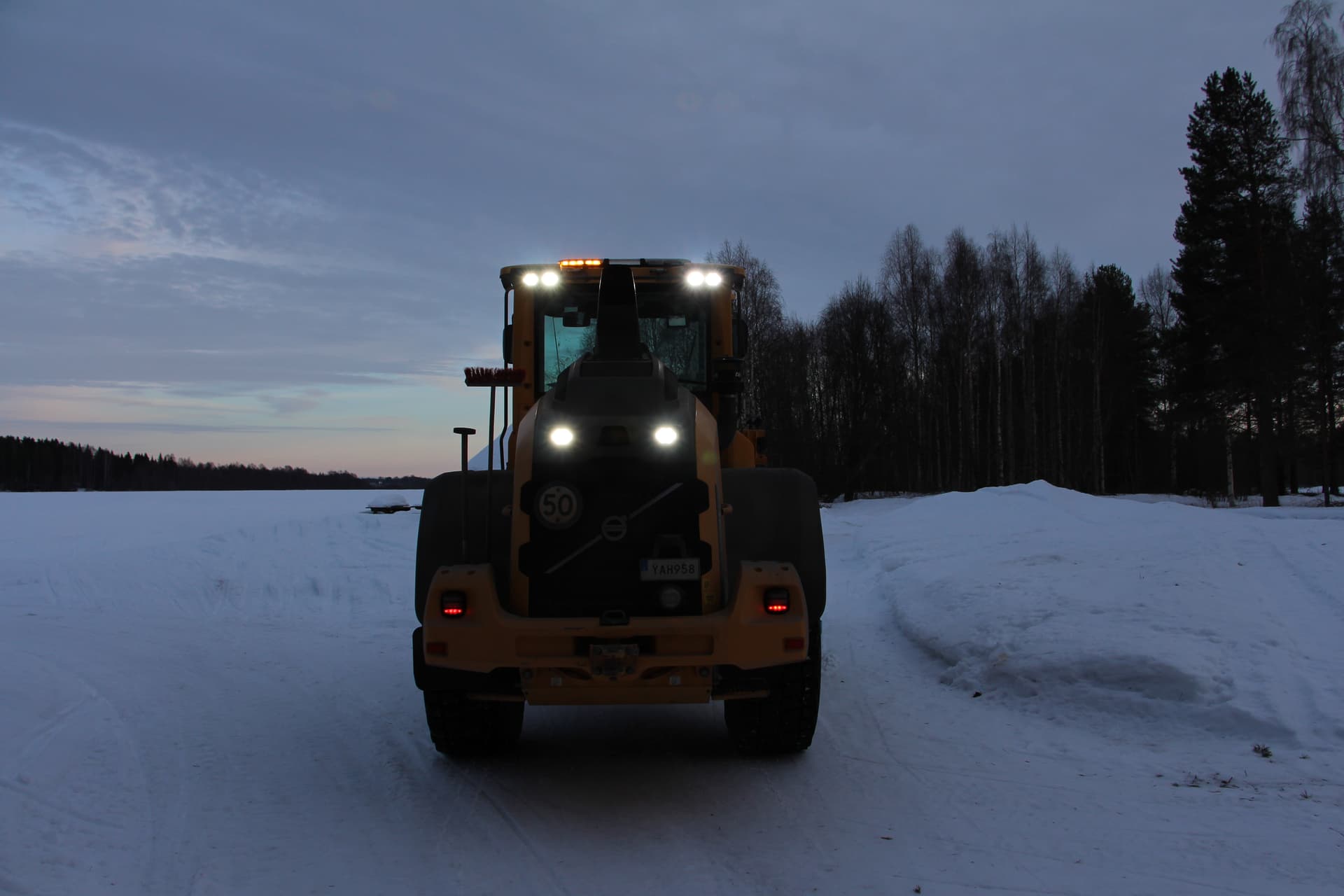 Brecabs hjullastare med tända arbetsljus i vinterkvällen