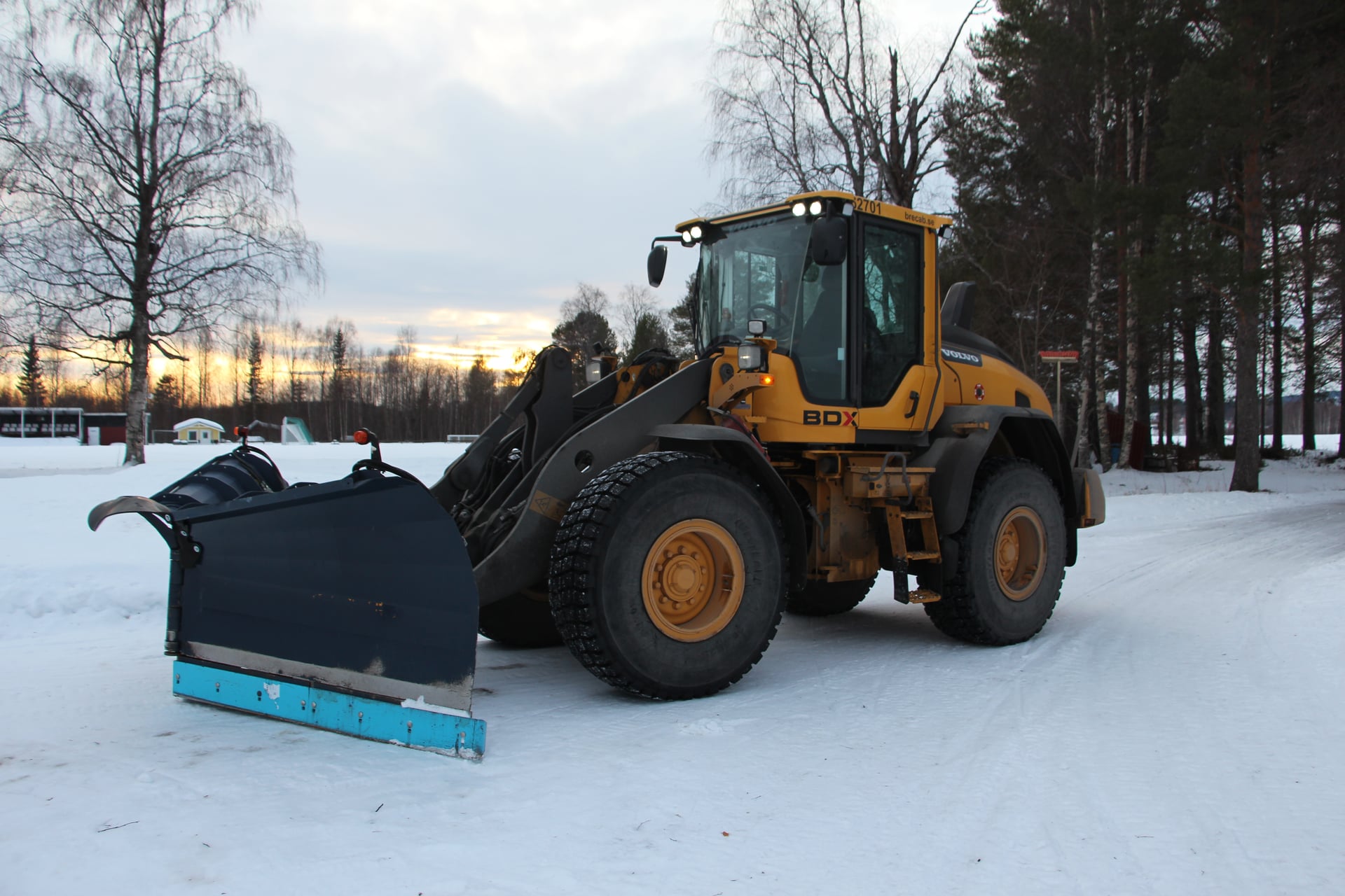 Brecabs gula hjullastare med snöplog i ett vinterlandskap i Boden